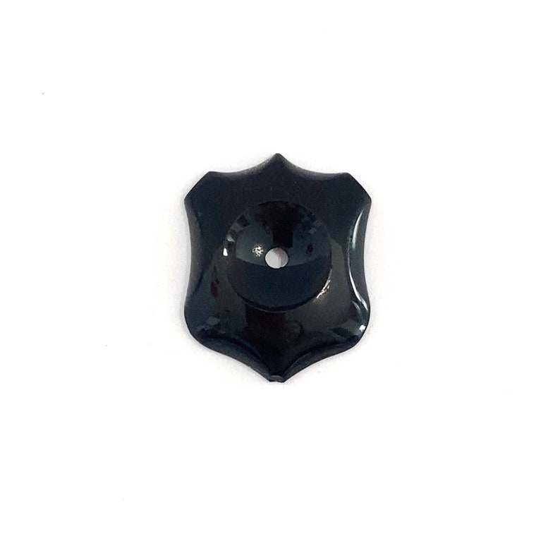 A black onyx shield shape cabochon polished loose gemstone. There is a small nick off the point. It has a concave drilled centre ideal for making a sleeve to set a gemstone. The base of the stone is flat ideal for making a piece of jewellery.