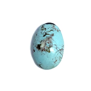 An oval polished cabochon pale blue turquoise loose gemstone with dark brown fine markings. It weighs 3.71 carats and measures 14x9mm. It would suit being made into a piece of jewellery. Pictured from the top of the loose stone on a white background.