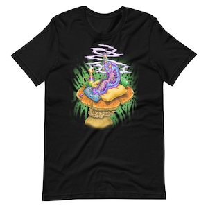 Könnte beinhalten: Ein schwarzes T-Shirt mit einer bunten Illustration einer Raupe, die auf einem Pilz sitzt, eine Pfeife raucht und von Rauch umgeben ist. Die Raupe trägt eine Krone und hat einen lila und blauen Körper mit grünen und gelben Akzenten.
