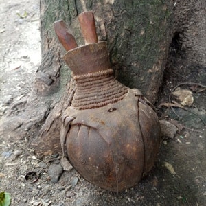 May include: A brown leather water bottle with a wooden stopper. The bottle is decorated with a woven band around the neck.