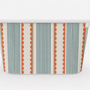 May include: Rectangular storage container with a white rim and handles. The exterior has a cream background with vertical teal stripes and alternating orange scalloped patterns. A decorative container for home storage.