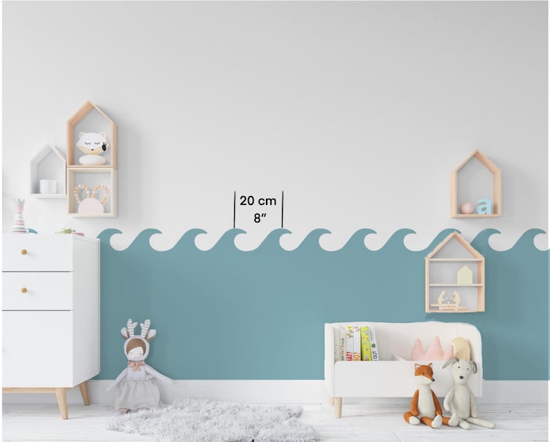 Op de afbeelding: Een witte muur met een blauwe golfrand, 20 cm of 8 inch hoog. De muur is versierd met houten planken en een knuffeldier.