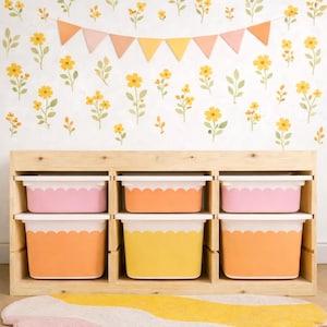 May include: A wooden storage unit with six colorful bins. The bins are in shades of pink, orange, and yellow, with scalloped edges. The background features a floral wallpaper and a banner.