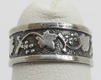 Puede incluir: Un anillo de banda de plata con un diseño de vid y hojas.