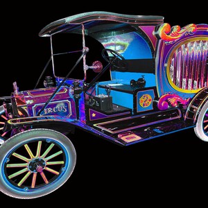 May include: A vintage-style, iridescent, black, blue, and pink car with a decorative, ornate, wooden, pipe organ in the back. The car has the word "CIRCUS" written on the side.