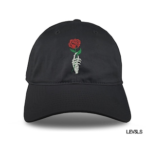 Puede incluir: Gorra de béisbol negra con un diseño bordado de una mano esquelética sosteniendo una rosa roja.