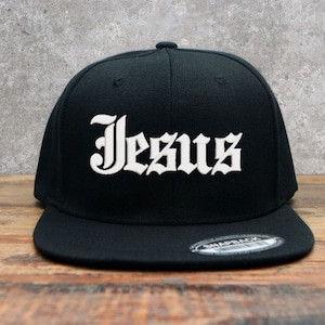 May include: Black baseball cap with a white "Jesus" inscription in a gothic font.