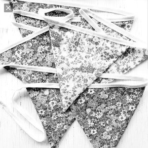 May include: A set of five black and white floral fabric bunting flags with white trim. The flags are arranged in a stack, with the top flag folded over the others.