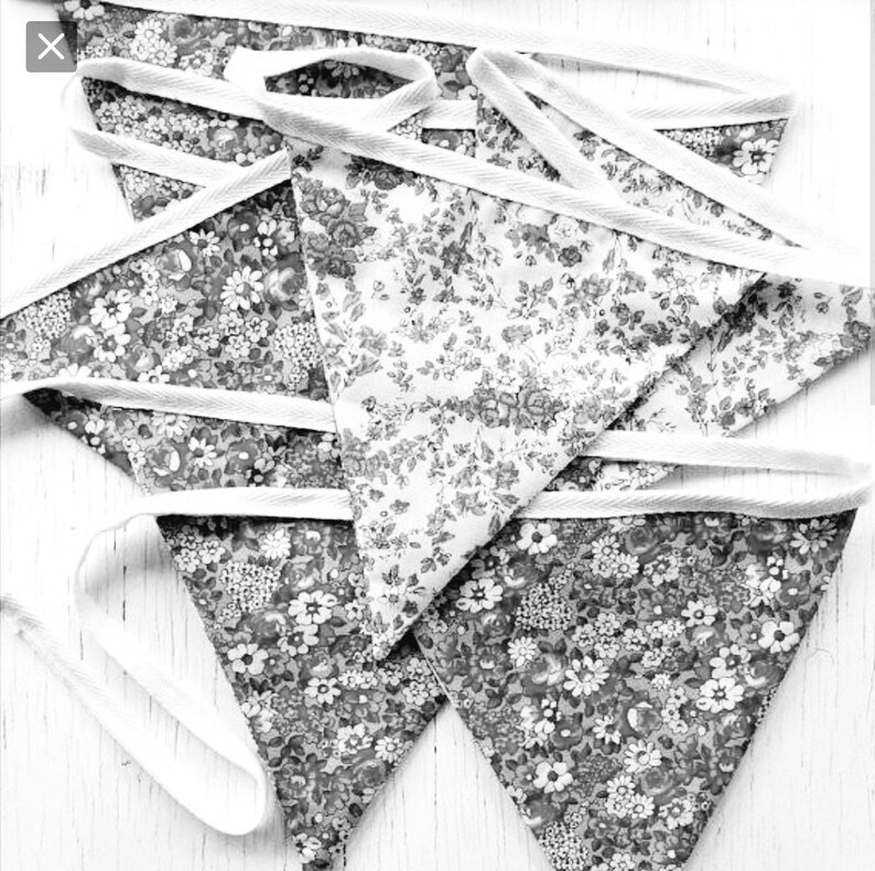 May include: A set of five black and white floral fabric bunting flags with white trim. The flags are arranged in a stack, with the top flag folded over the others.