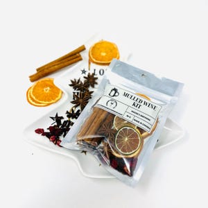 May include: A clear plastic bag containing a mulled wine kit. The kit includes cinnamon sticks, star anise, dried orange slices, and dried cranberries. The bag has a label that reads "Mulled Wine Kit" and "Makes 6 Servings".