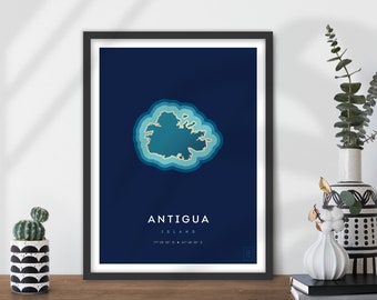 May include: A blue and gold print of the island of Antigua. The island is outlined in gold and has a layered blue effect. The text "ANTIGUA ISLAND 17°06'57" N • 61°48'00" W" is printed below the island.