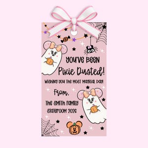 May include: A rectangular pink gift tag with a white and pink ribbon bow at the top. The tag features two white ghost characters with mouse ears and bows holding pumpkins, a spider, spiderwebs, stars, and the text: You've Been Pixie Dusted! Wishing you the most magical day! From, The SMITH FAMILY STATEROOM 2026.