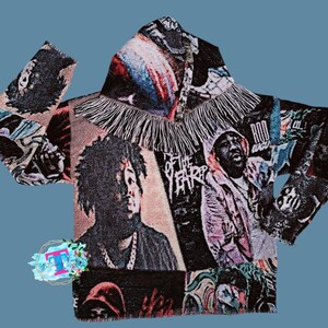 May include: A black hooded sweatshirt with a colorful tapestry design featuring various images of people and text, including "God Wave" and "Rod Wave". The sweatshirt has a fringe trim around the hood.
