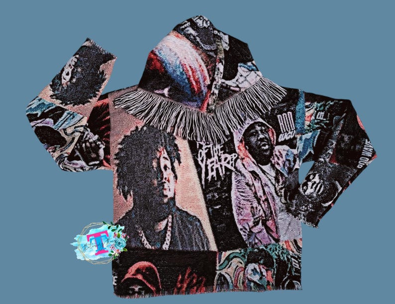 May include: A black hooded sweatshirt with a colorful tapestry design featuring various images of people and text, including "God Wave" and "Rod Wave". The sweatshirt has a fringe trim around the hood.