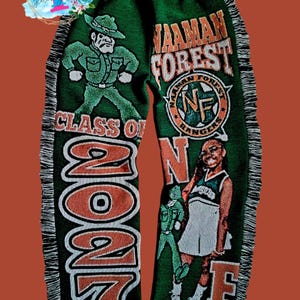 Puede incluir: Manta tejida verde y naranja con las palabras "Wauman Forest" y "Class of 2027". La manta presenta un guardabosques de dibujos animados y una animadora.