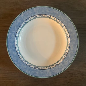 May include: A blue and white ceramic soup bowl with a floral design. The bowl has a wide rim and a shallow depth.