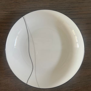 Peut inclure: Bol en céramique blanc avec un motif de vagues noir et gris. Le bol a un bord noir et une finition lisse et brillante. Convient pour servir des soupes, des salades ou d'autres plats. Diamètre environ 20 cm.