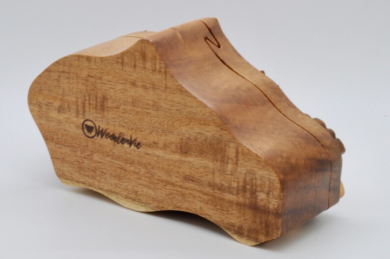 Op de afbeelding: Een houten doos met een unieke, organische vorm. De doos is gemaakt van lichtbruin hout met een natuurlijk houtnerfpatroon. De doos is gesloten en heeft een klein, gegraveerd logo aan de voorkant met de tekst "WooderVie".