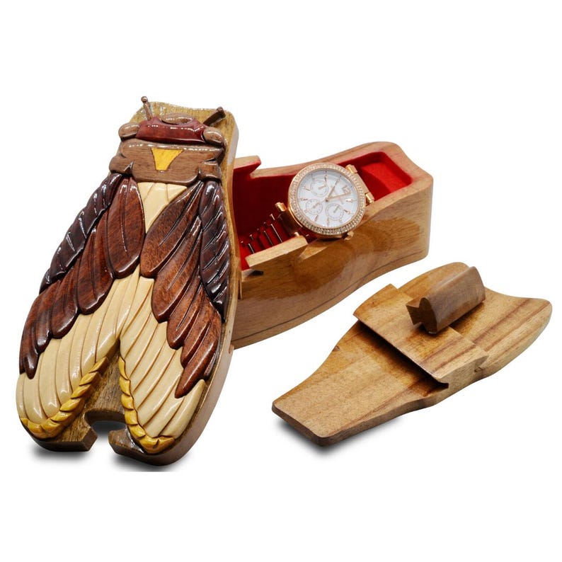 May include: A wooden puzzle box shaped like a cicada with intricate carvings. The box is open, revealing a red velvet interior and a watch inside.