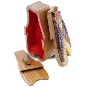 May include: A wooden puzzle box shaped like a penguin with a red felt interior. The box is open and the lid is off, revealing the intricate wooden puzzle pieces that make up the penguin's body.