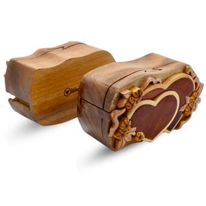 May include: A wooden puzzle box with a double heart design. The box is intricately carved with floral details and has a natural wood finish.