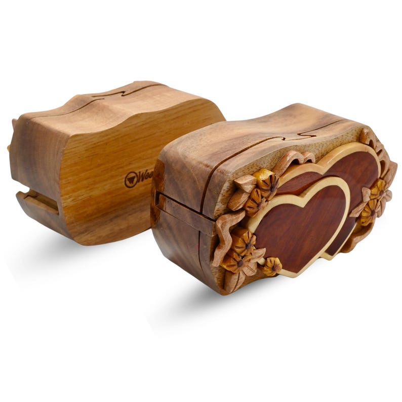 May include: A wooden puzzle box with a double heart design. The box is intricately carved with floral details and has a natural wood finish.