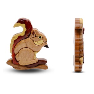 May include: A wooden squirrel puzzle, featuring a detailed design with various wood tones. The squirrel is posed on a branch, with a side view of the puzzle also shown. The puzzle is approximately 5 inches long.