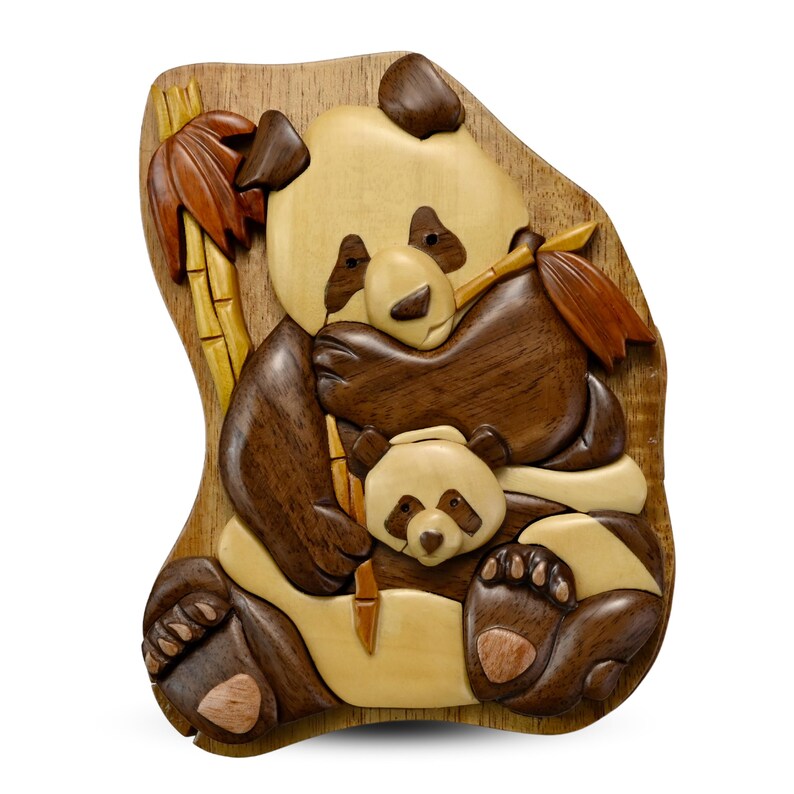 Puede incluir: Una caja de rompecabezas de madera con una imagen tallada de dos pandas, uno grande y uno peque&ntilde;o, sosteniendo tallos de bamb&uacute;. La caja est&aacute; hecha de diferentes tonos de madera marr&oacute;n y tiene un acabado de madera natural.