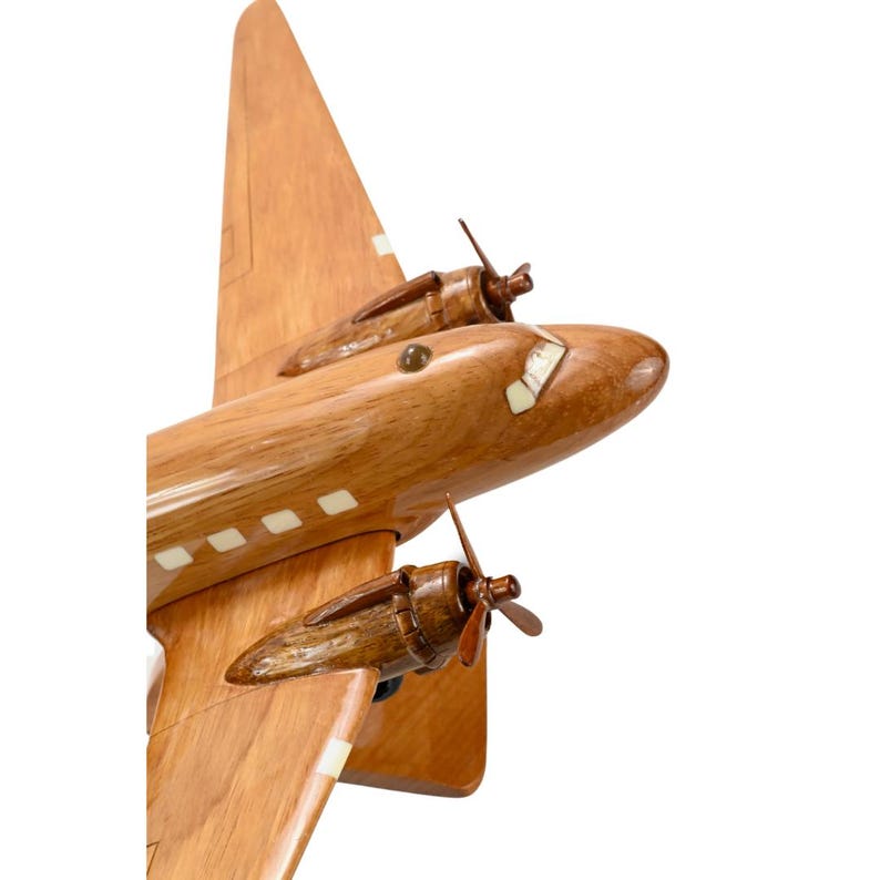 K&ouml;nnte beinhalten: Ein Holzmodell eines Flugzeugs mit zwei Propellern. Das Modell ist in einem nat&uuml;rlichen Holzfinish mit wei&szlig;en Akzenten lackiert. Das Flugzeug ist auf einem Holzsockel montiert.