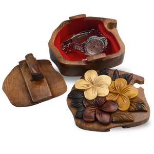 May include: A wooden puzzle box with a carved floral design. The box is open and a watch is inside. The box is made of dark wood and has a red velvet lining.