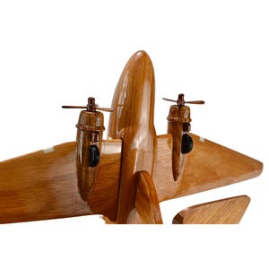 K&ouml;nnte beinhalten: Ein Holzmodell eines Flugzeugs mit zwei Propellern. Das Flugzeug ist aus hellem braunem Holz gefertigt und hat eine nat&uuml;rliche Oberfl&auml;che. Die Propeller sind aus dunklem braunem Holz gefertigt und haben eine schwarze Oberfl&auml;che.