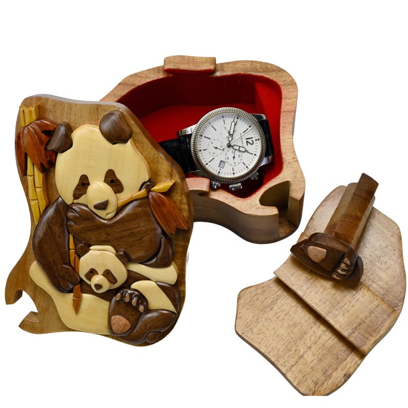 Puede incluir: Una caja de rompecabezas de madera con un dise&ntilde;o de oso panda. La caja est&aacute; abierta y hay un reloj en su interior. La caja est&aacute; hecha de madera marr&oacute;n claro y tiene un forro de fieltro rojo.