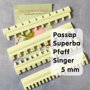 Può includere: Guide per macchine da cucire in plastica giallo pallido con bordo dentellato. Le guide sono etichettate con il testo "Passap Superba Pfaff Singer 5 mm". Sullo sfondo un biglietto da visita con la scritta "my creative land handmade studio".