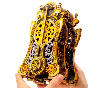 May include: A wooden clockwork model with intricate details and a gold and black color scheme. The clockwork is visible and has a decorative design.
