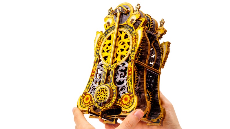 May include: A wooden clockwork model with intricate details and a gold and black color scheme. The clockwork is visible and has a decorative design.