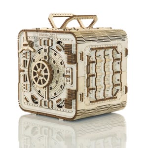 May include: A wooden model of a safe with a combination lock and a handle. The safe is made of light wood and has a natural finish. The safe is a 3D puzzle that can be assembled.