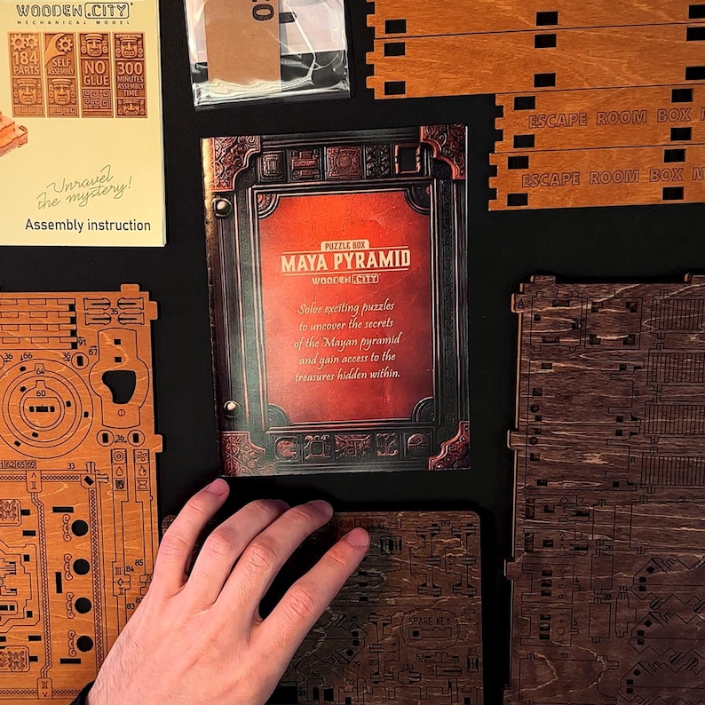 Puede incluir: Un kit de rompecabezas de madera con el texto "MAYA PYRAMID" y "WOODEN CITY" en la portada. El kit incluye piezas de madera, instrucciones de montaje y el texto "Unravel the mystery!". El kit tiene 184 piezas y no requiere pegamento.