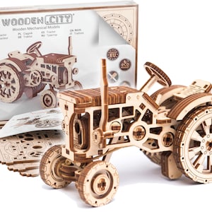May include: A wooden model kit of a tractor. The kit is made of laser-cut wood and comes with all the pieces needed to build the tractor. The tractor is a classic design with a large front wheel and a smaller rear wheel. The kit is packaged in a box with the words "WOODEN.CITY" printed on it.
