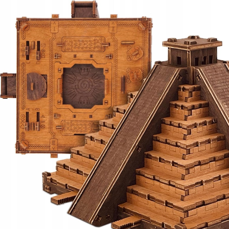 Puede incluir: Una caja de rompecabezas de madera y una maqueta de pir&aacute;mide maya. La caja es rectangular con intrincadas tallas y un dise&ntilde;o circular en el centro. La pir&aacute;mide tiene m&uacute;ltiples niveles y una escalera central, todo en tonos marrones.