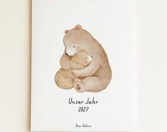 May include: A wall calendar featuring a watercolor illustration of a large brown bear hugging a small bear cub. The text "Unser Jahr 2027" and "Bear Nature" is printed in black below the bears. The calendar is bound with a white wire coil.