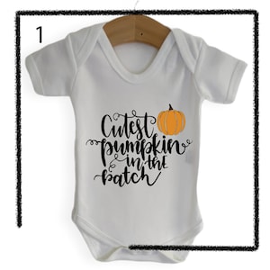 May include: White baby onesie with black text that reads "Cutest pumpkin in the patch" and a small orange pumpkin graphic.