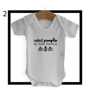 May include: White baby onesie with black text that reads "cutest pumpkin in the patch" and three black pumpkin illustrations.