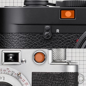 May include: Detailed view of two vintage rangefinder cameras. One is black with a textured leatherette grip, the other is silver. Both feature orange accents, including the shutter button and frame counter.