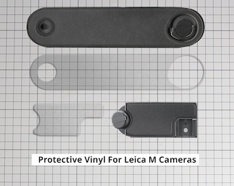May include: Protective vinyl accessories for Leica M cameras. The image shows several black vinyl pieces, including a top plate, a base plate, and a clear vinyl screen protector. The text "Protective Vinyl For Leica M Cameras" is displayed.