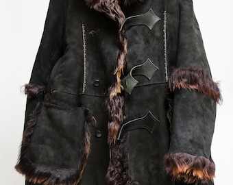 May include: A long black shearling coat with a brown fur collar and trim. The coat has a button closure and two pockets.