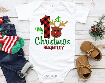 May include: White baby onesie with a red and black plaid number one, a red-nosed reindeer, and the text "My 1st Christmas Brantley".
