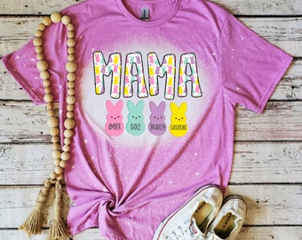 May include: Pink t-shirt with a bleach-splattered design featuring the word "MAMA" in a colorful Easter bunny pattern. The shirt has four smaller Easter bunny designs with the names "Amber", "Cole", "Bradley", and "Catherine" underneath.