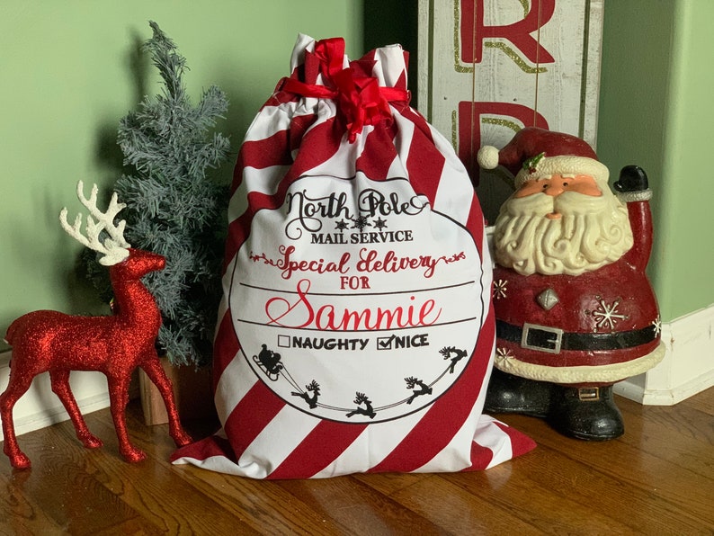 May include: Red and white striped Christmas stocking with a black and white label that says "North Pole Mail Service Special Delivery For Sammie Naughty Nice".