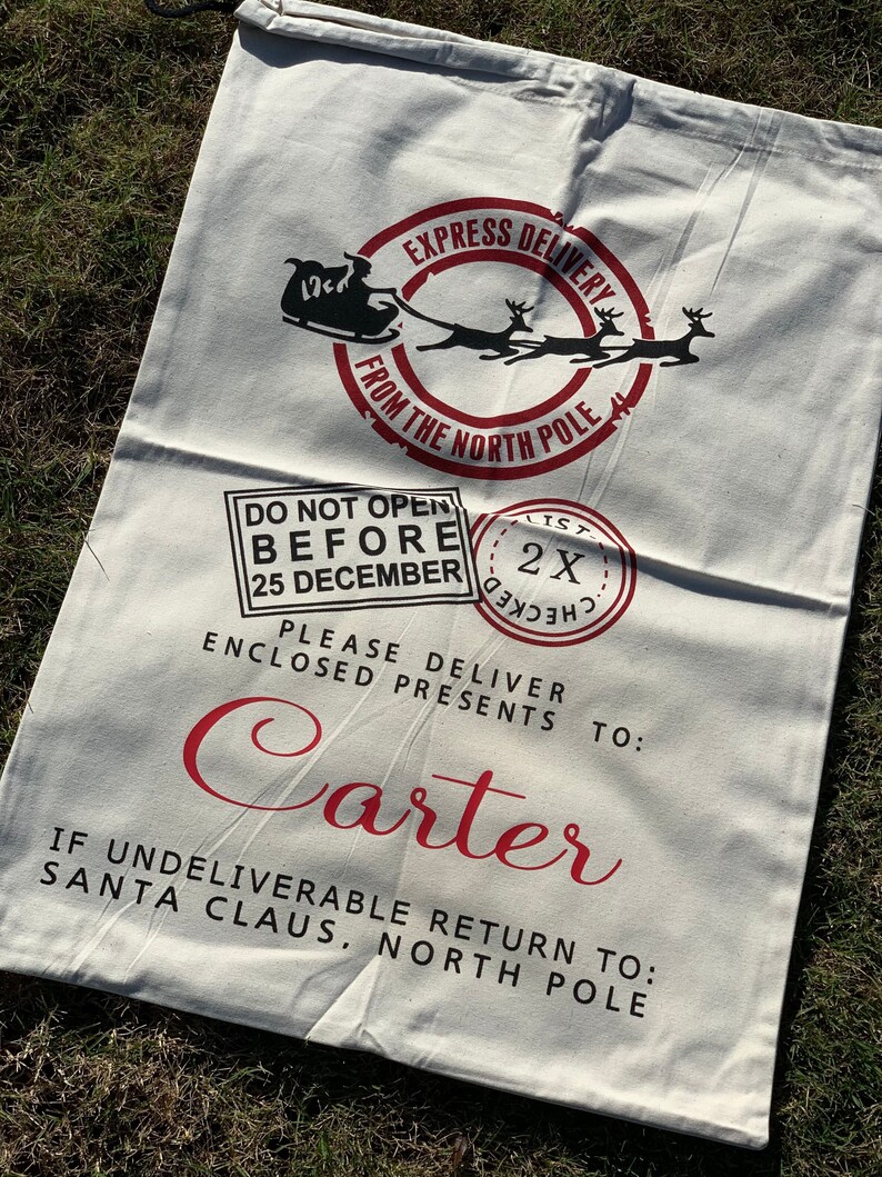 May include: White canvas Santa sack with red text and graphics. The text reads "Express Delivery from the North Pole", "Do Not Open Before 25 December", "Please Deliver Enclosed Presents To: Carter", and "If Undeliverable Return To: Santa Claus, North Pole".