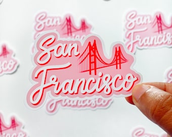 May include: Pink and red sticker with the text "San Francisco" in a cursive font. The sticker features a red outline of the Golden Gate Bridge.